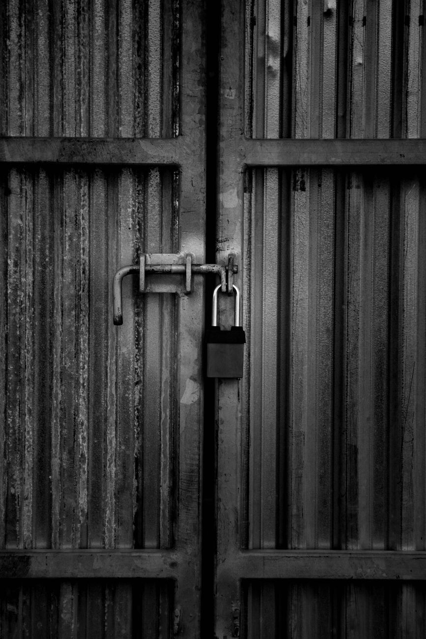 grayscale photo of padlock on door